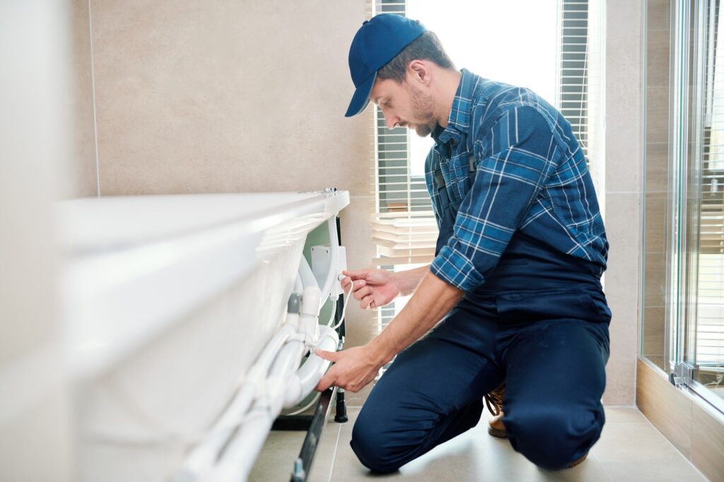 Professional plumber installing bathtub replacement